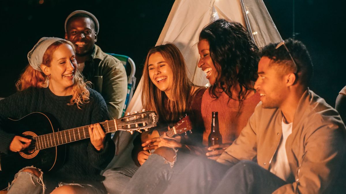 Grupo de amigos tocando la guitarra junto a una fogata